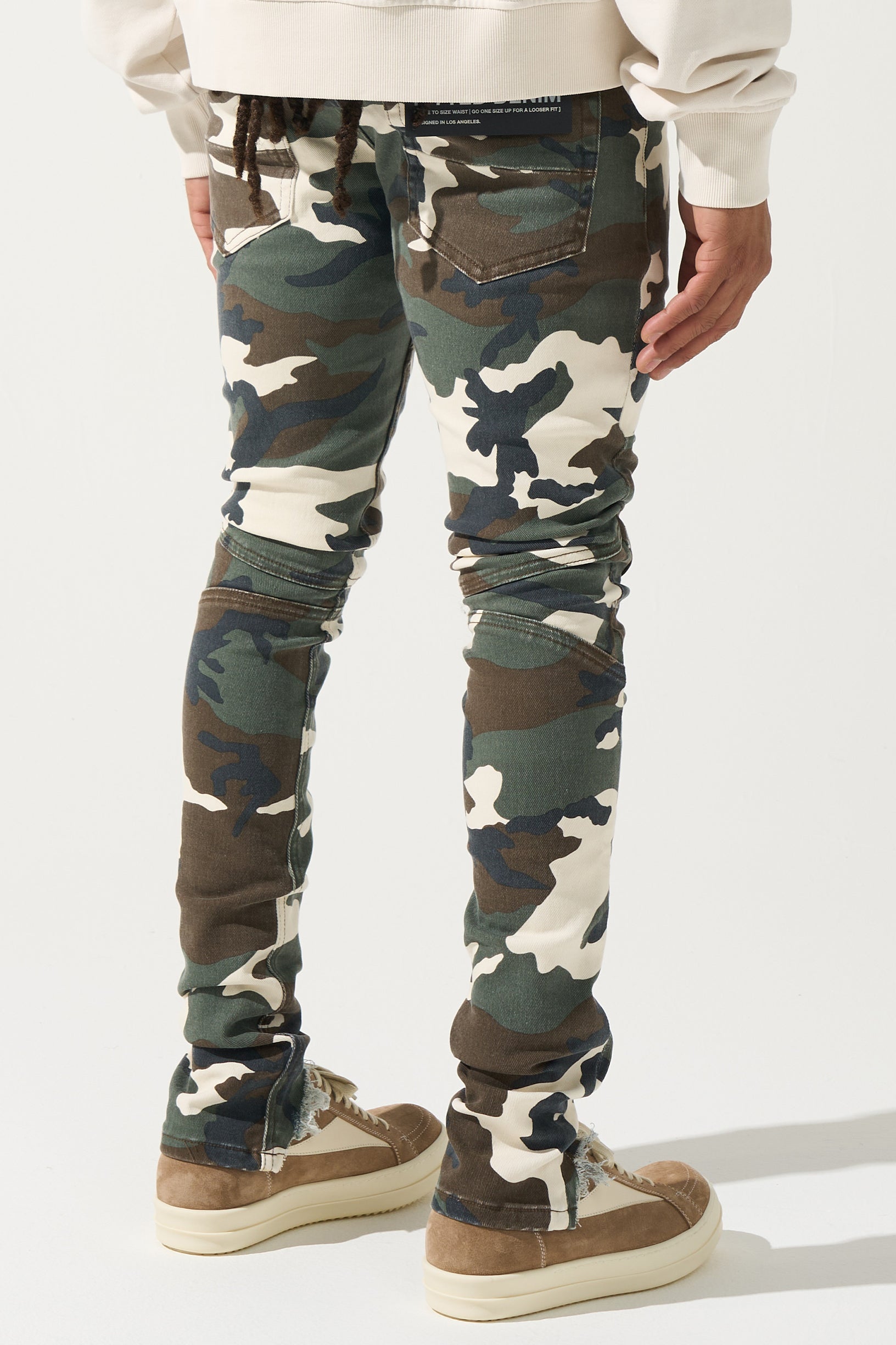 SERENEDE® SYNC Jeans in desert moss camo with fitted construction, biker panel details, embroidered [S]® logo, and holographic hangtag.