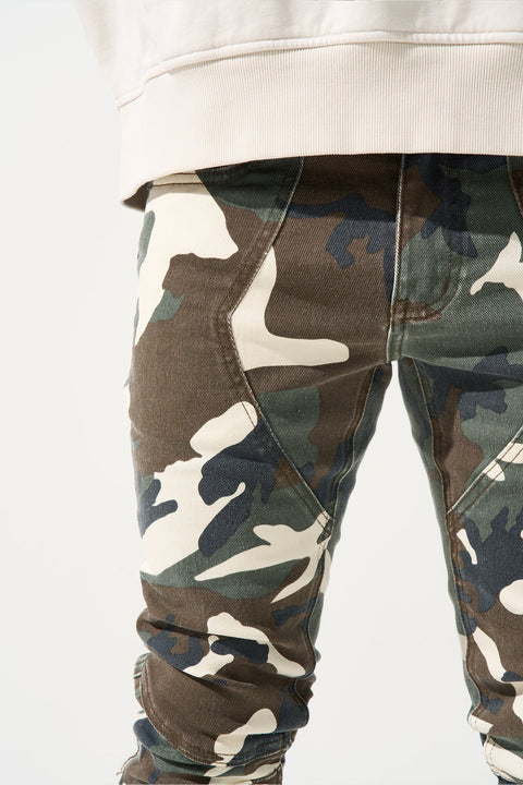 SERENEDE® SYNC Jeans in desert moss camo with fitted construction, biker panel details, embroidered [S]® logo, and holographic hangtag.