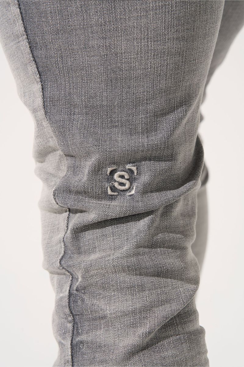 SERENEDE® TITAN skinny jeans in faded grey wash with five-pocket styling, tonal stitching, and leather logo waistband patch.